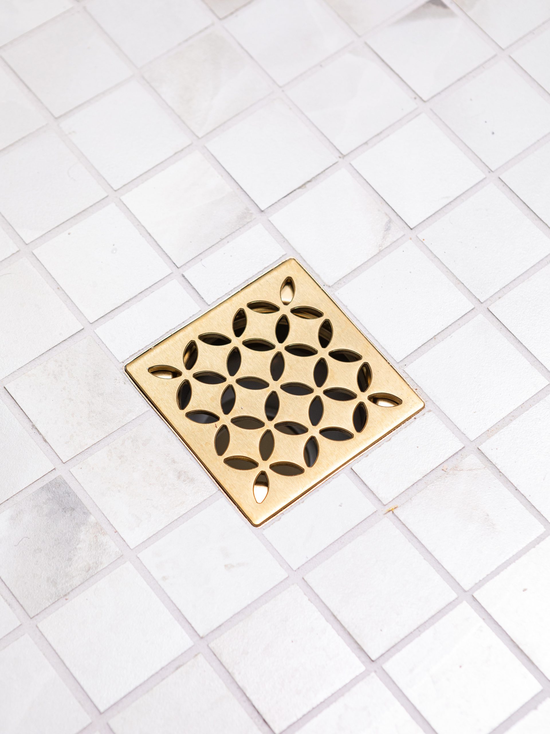 white tiled floor with golden drain